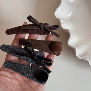 Detail view of winter tweed hair clips with leather bows and plush pom-poms set