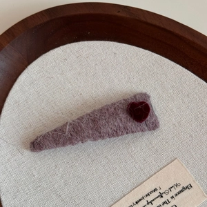 Detail of purple velvet hair clip with a red flocking heart on a wooden tray