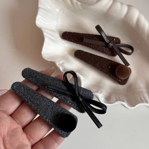 Detailed shot of felt hair clips with leather bows and plush pom poms in grey and brown