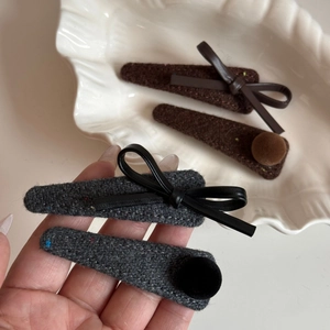 Close-up of tweed fabric hair clips with leather bows and plush balls in autumn colors