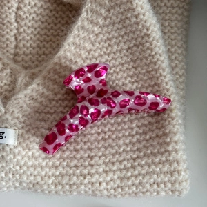 Close-up of pink leopard print cellulose acetate hair claw clip on soft knit sweater