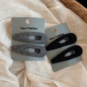 Close-up of plush wool-like teardrop BB hair clips in dark grey and black on card packaging