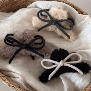 Detail view of plush bow hair claws in beige, brown and black for winter hairstyles