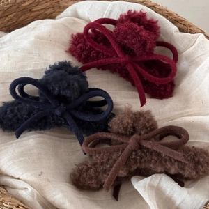 Trio of plush bow hair claws in burgundy, black and coffee colors on white linen