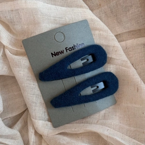 Close-up of navy blue velvet teardrop hair clips on card set against a beige fabric background
