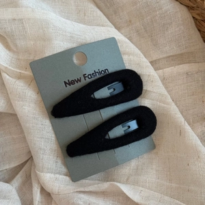 Close-up of a pair of plush black BB hair clips on a New Fashion display card