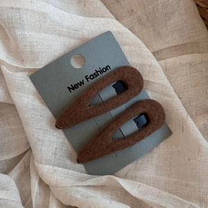 Detailed close-up of brown plush teardrop BB hair clips on a card display base