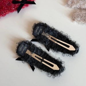 Detail showing plush black bow hair clip with silver metal BB base and Handmade label