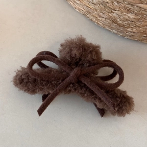 Detail of plush dark coffee hair claw with faux fur, soft ribbon bow and fuzzy ball decoration