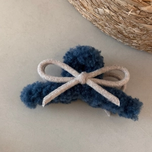 Detailed view of the dark blue plush faux fur hair claw clip with a beige bow decoration