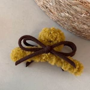 Detail of yellow plush bow hair claw clip with warm faux fur texture for winter