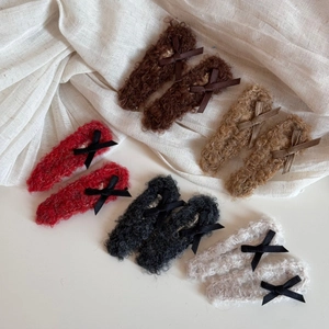 Set of ten plush bow hair clips in multiple autumn colors on soft white fabric background