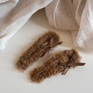 Close-up of brown plush bow hair clips with soft fuzzy texture and satin ribbon detail