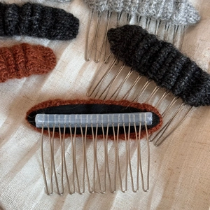 Close-up detail of knitted 10-tooth metal hair combs in black, brown, and grey colors