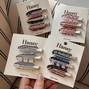 Detailed view of three-piece checkered hair clips set with heart and bear patterns on cards