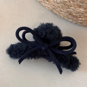 Close-up of navy blue plush bow hair claw clip with warm faux fur texture
