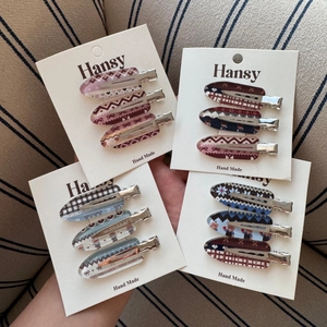 Handheld set of four colorful plaid and heart pattern hair clips on display card