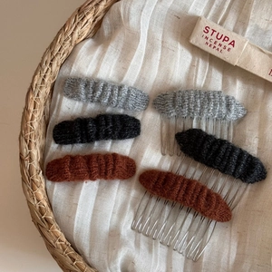 Detail of knitted wool hair clips and side combs in grey, black and brown colors