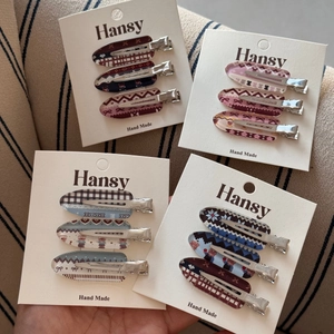 Detail of four sets of patterned metal hair clips with check and bear prints on cards