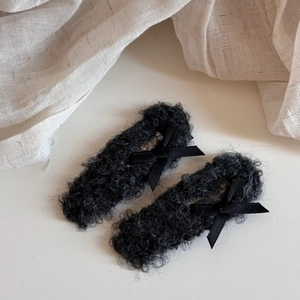 Close-up of black plush bow hair clips with soft faux fur texture for winter