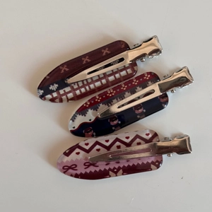Close-up of three checkered acrylic hair clips with diverse vintage patterns and silver metal clips