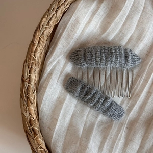 Detailed view of dark grey knitted hair clip and comb with soft wool texture on linen