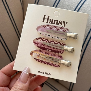 Set of three acrylic duckbill hair clips with retro pink and purple patterns on a card