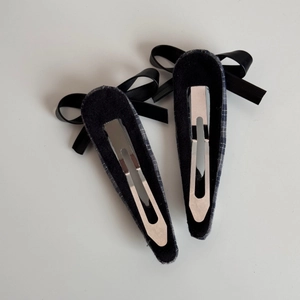 Detail of silver metal clips with navy plaid fabric and black ribbon bows on back