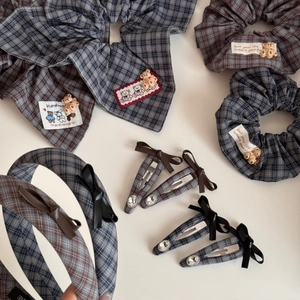 Detailed view of blue plaid hair accessories with plush bear and ribbon bow decorations