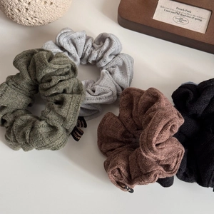 Detail of chunky knit scrunchies in olive, grey and brown with retro woven texture