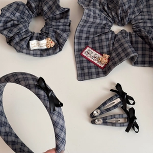 Flat lay of gray plaid hair accessories with teddy bear scrunchie and bow clips