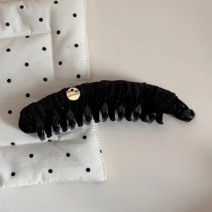 Détail de la pince banane en velours noir avec un médaillon doré pour cheveux épais