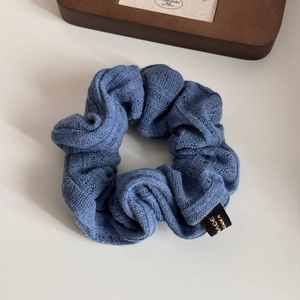 Detailed view of blue knitted scrunchie texture with hollow floral crochet pattern