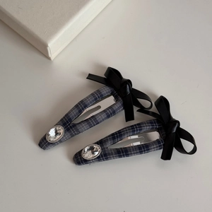 Detail of blue plaid bow hair clips with black faux leather and large crystal embellishment