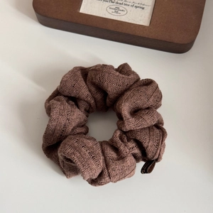 Detailed close-up of dark brown knitted scrunchie texture with hollow out stitch pattern