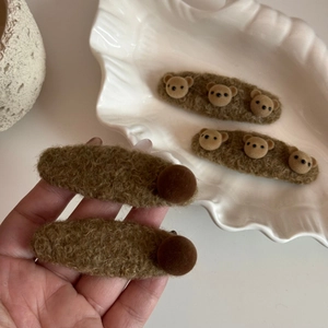 Détail de pinces à cheveux ours en peluche avec tissu sherpa et pompons doux pour l'automne