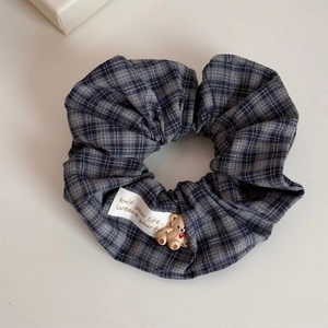 Close-up of checkered scrunchie with cute brown bear charm and embroidered fabric label