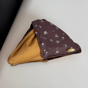 Detailed close-up of floral fabric hair claw clip with golden metal decorative brand label