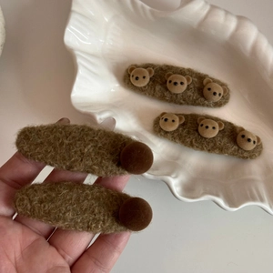 Détail des barrettes à cheveux ours en peluche marron montrant la texture douce et les boules