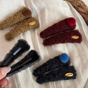 Détail de pinces à cheveux triangulaires en peluche avec étiquette dorée et texture
