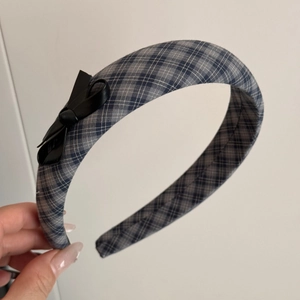 Detail showing grey-blue plaid fabric headband with a stylish black leather bow