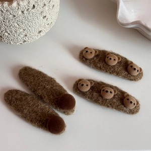 Détail des barrettes en peluche ours brun avec texture douce et design mignon en relief