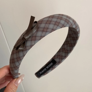 Detail of plaid headband featuring brown leather bow and handmade label in retro style