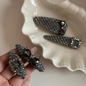 Detailed macro view of four-piece BB hair clip set with black heart rhinestones and silver crystals