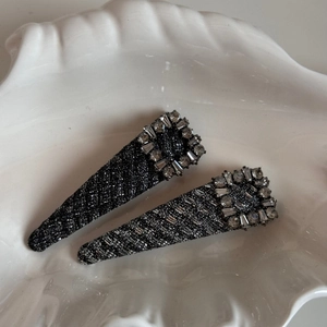 Detailed macro view of gray tweed fabric hair clips with sparkling crystal rhinestone buckles