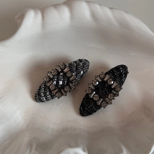 Close-up of elegant tweed and rhinestone BB hair clips on a decorative white shell tray