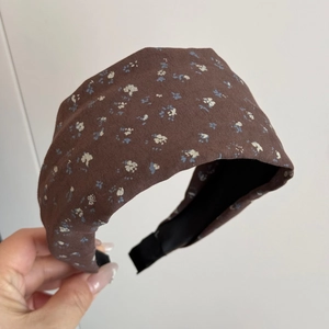 Detail of a wide brown floral headband with vintage blue flower patterns and pleated fabric