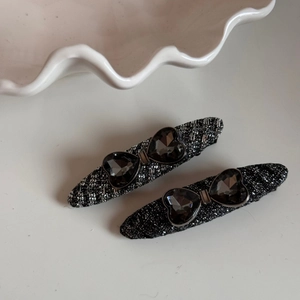 Detail of tweed fabric hair clips with heart-shaped grey crystals in bow design