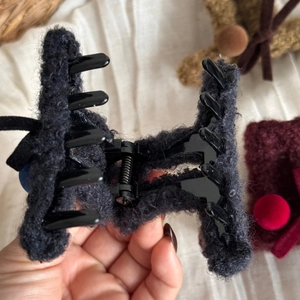 Dettaglio della molletta per capelli nera con trama in peluche e molla in metallo