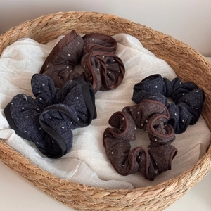 Set of four polka dot knit hair scrunchies in brown and navy blue within a basket